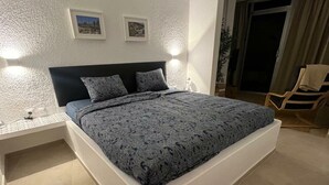 A bedroom with a bed, nightstands, and a chair. - Villa Faro Studio 2 (Pajara)