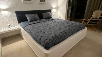 Un dormitorio con cama, mesitas de noche y una silla.