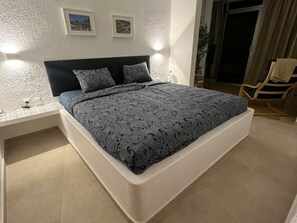 A bedroom with a bed, nightstands, and a chair. - Villa Faro Studio 2 (Pajara)