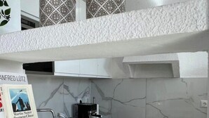 A modern kitchen with white cabinetry, a coffee machine, and decorative cactus plants. - Villa Faro Studio 2 (Pajara)