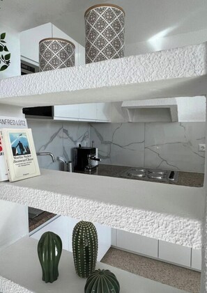 A modern kitchen with white cabinetry, a coffee machine, and decorative cactus plants. - Villa Faro Studio 2 (Pajara)