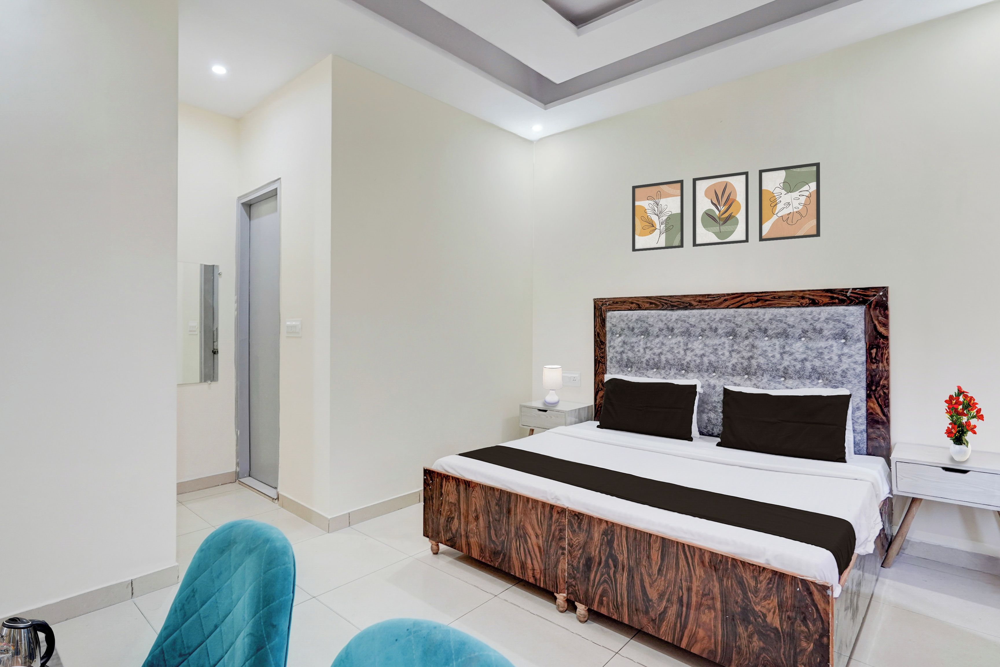 A modern hotel room with a large bed, a nightstand, a chair, and a door.