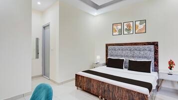 A modern hotel room with a large bed, a nightstand, a chair, and a door.