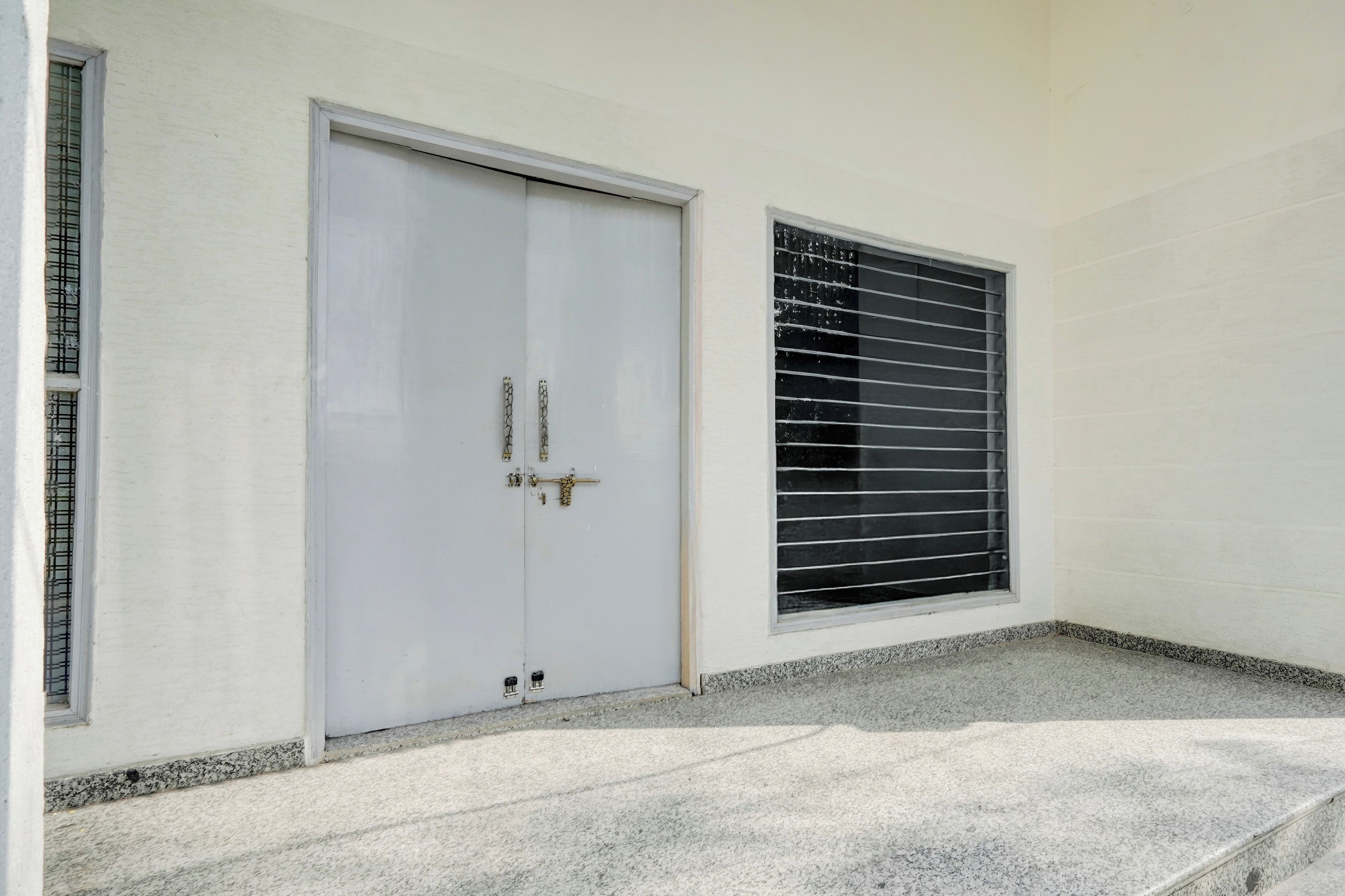 Una puerta blanca con manija y una ventana con persianas horizontales.