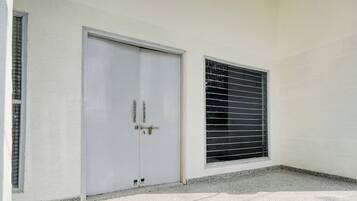 Una puerta blanca con manija y una ventana con persianas horizontales.