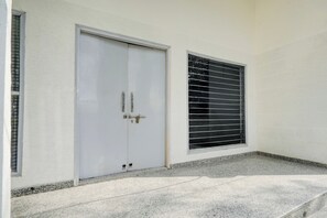 Una puerta blanca con manija y una ventana con persianas horizontales.