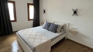Une chambre à coucher comprenant un lit, une table de chevet, une commode, une fenêtre et un luminaire fixé au mur.