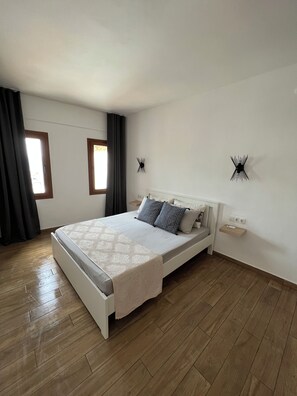 Una camera da letto con un letto, un comodino, una lampada a parete e una finestra.