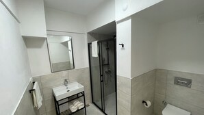 Une salle de bain moderne avec un lavabo blanc, un miroir et des toilettes.