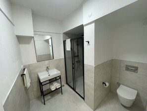 Un bagno moderno con lavandino, specchio e water bianchi.