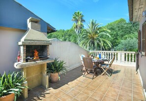 Eine Terrassengruppe im Freien mit einem eingebauten Grill, Blumentöpfen und einer Essgruppe mit Stühlen und Tisch.