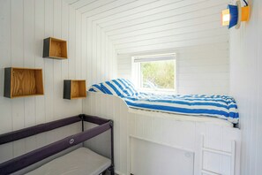 A room with a bunk bed, a small window, and wooden storage boxes on the wall. - Architect-designed home with a maritime look (Sjællands Odde)