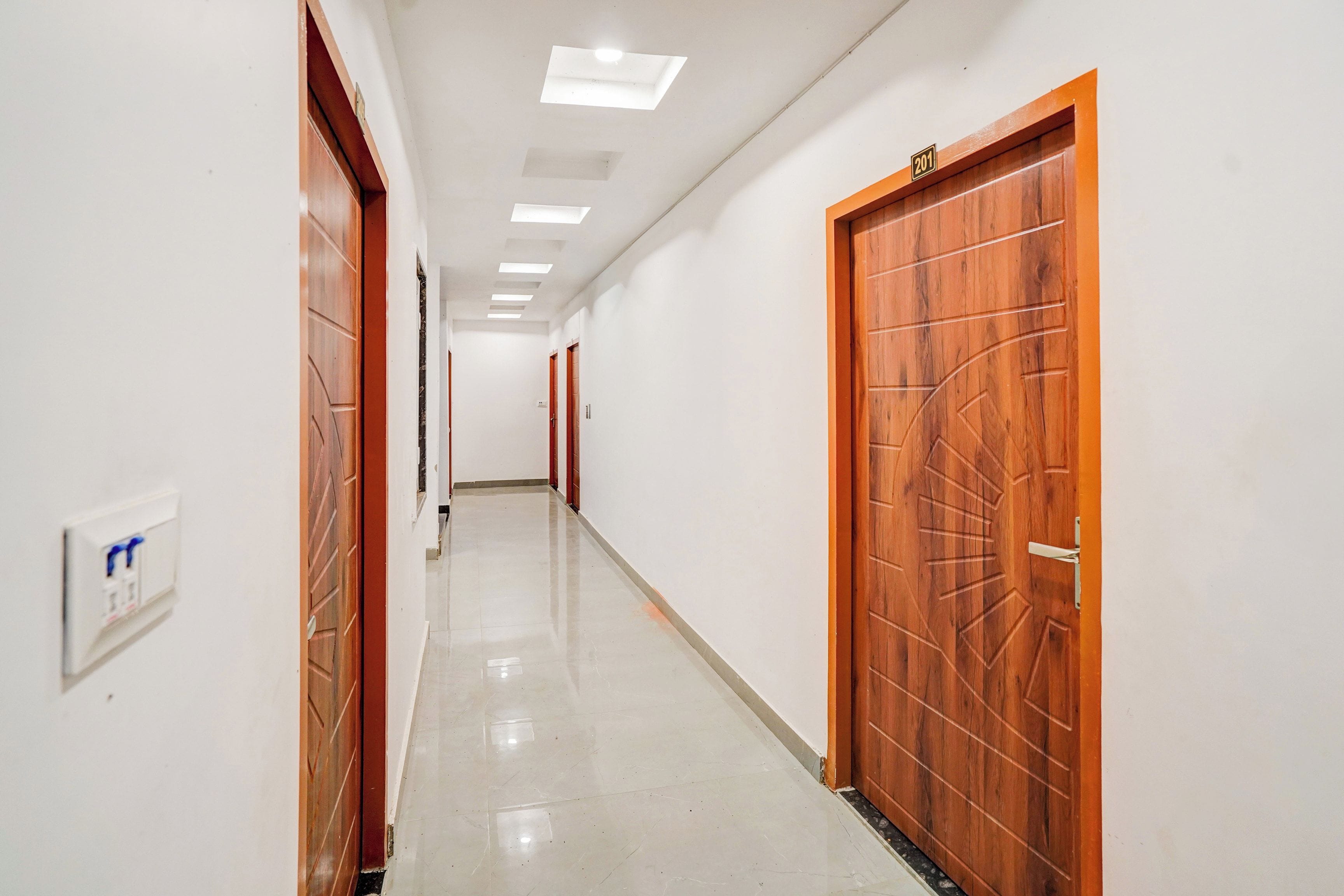 A hallway with wooden doors, a light switch, and a ceiling with recessed lighting.