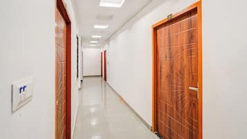 A hallway with wooden doors, a light switch, and a ceiling with recessed lighting.