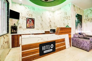 Une chambre d’hôtel avec un lit en bois, un comptoir d’accueil et un canapé violet.