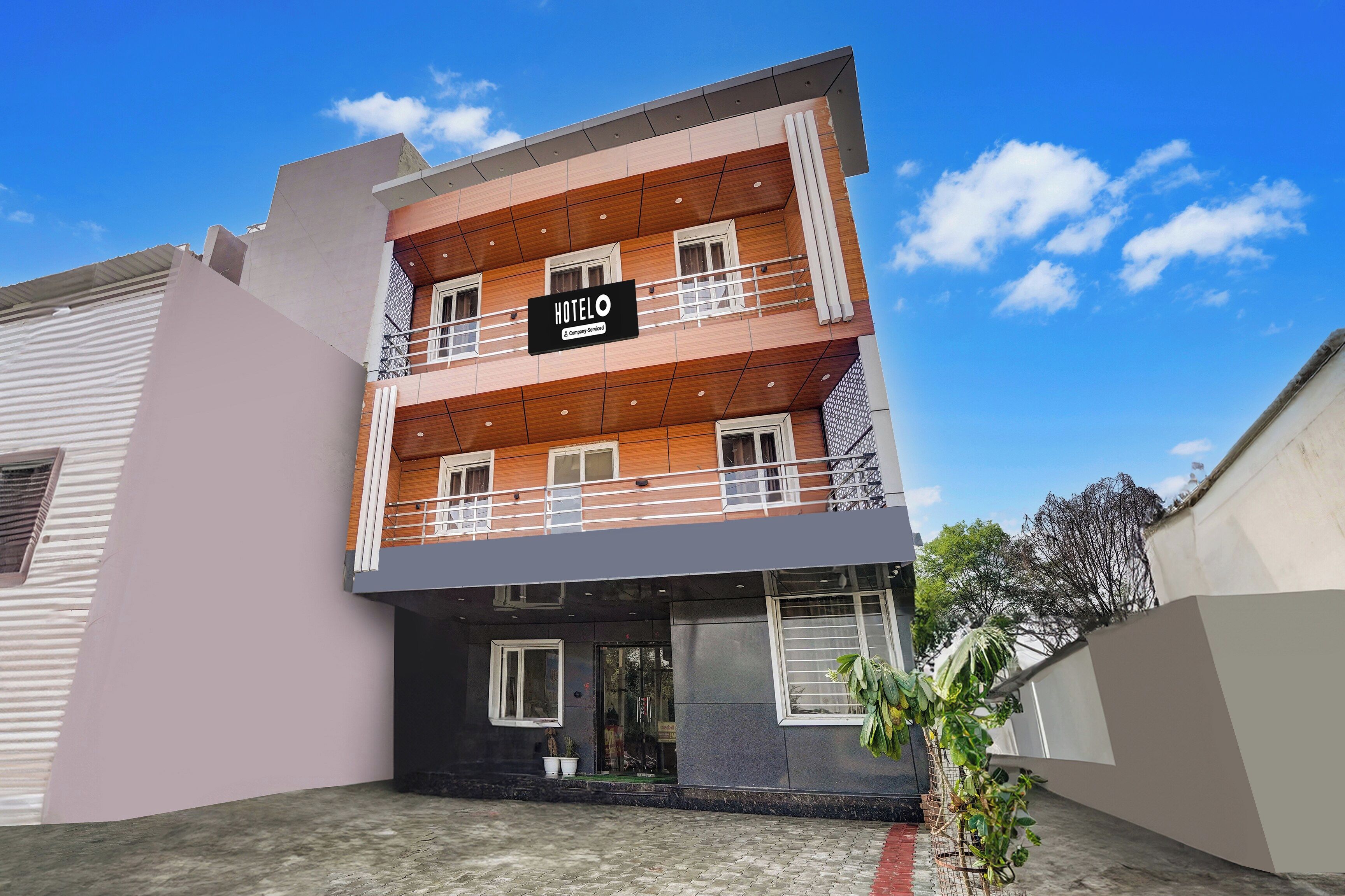 A multi-story hotel with a 'HOTELO' sign, balconies, and a paved entrance area.