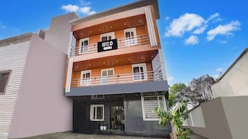 A multi-story hotel with a 'HOTELO' sign, balconies, and a paved entrance area.