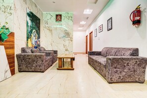 A hotel lobby with marble flooring, a reception desk, sofas, and a fire extinguisher on the wall. - Hotel O Sunrakh Road Vrindavan Formerly (Vrindavan)