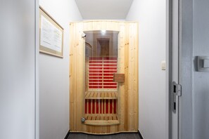 Eine Sauna mit Holztür, einer Bank und einem Glasfenster.