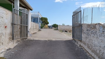 A gated entrance to a building with a paved driveway leading to a parked car.