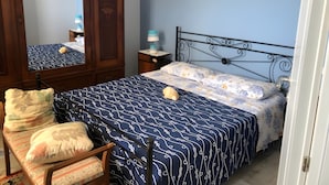 Une chambre à coucher comprenant un lit, une chaise, une armoire, une table de chevet et une fenêtre donnant sur un beau paysage.
