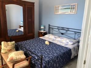 Une chambre à coucher comprenant un lit, une chaise, une armoire, une table de chevet et une fenêtre donnant sur un beau paysage.
