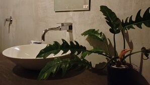 Ein Badezimmer mit einem weißen Waschbecken, einem Spiegel und einer Topfpflanze.