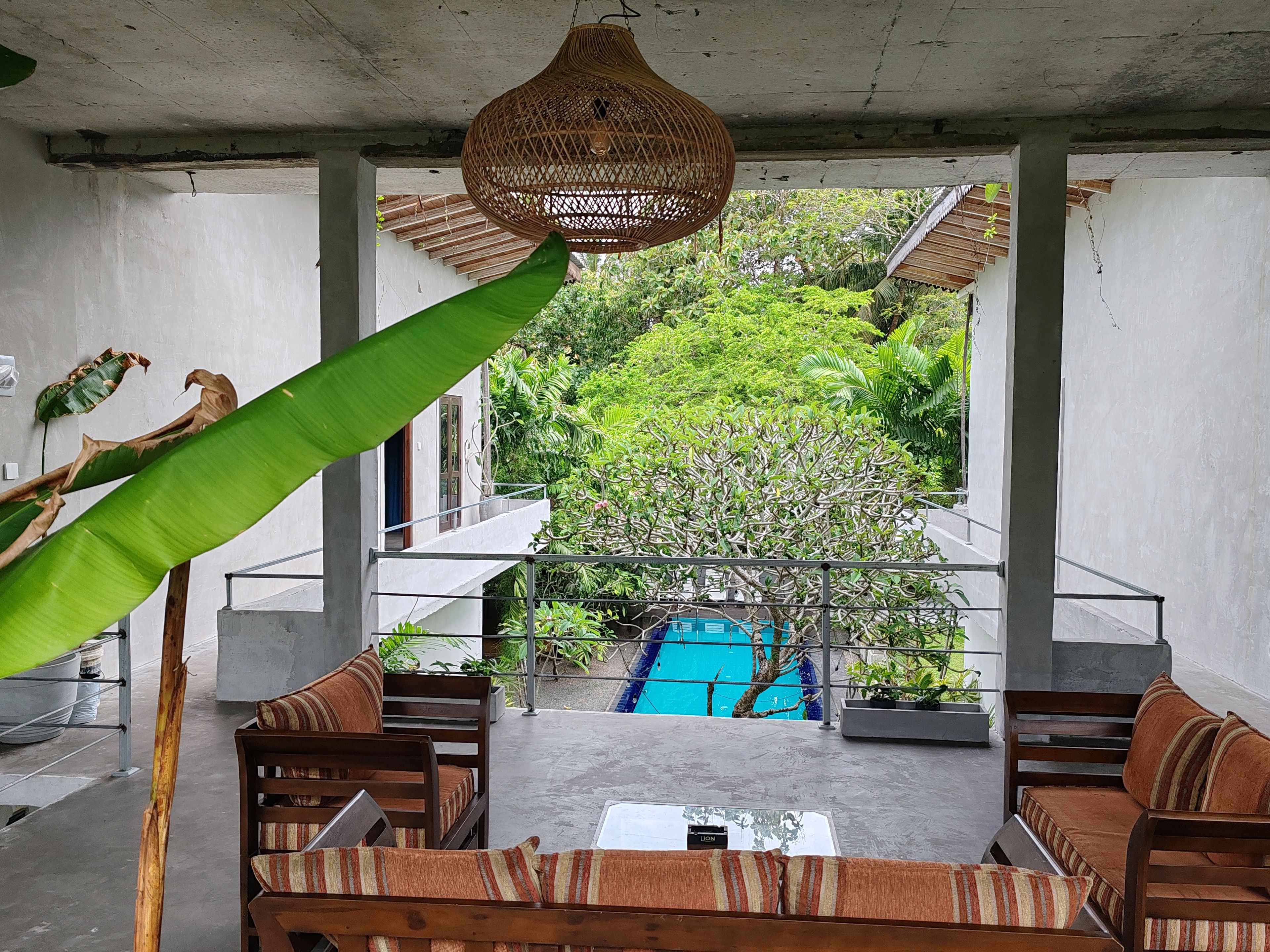 A modern outdoor seating area with a pool, surrounded by lush greenery.