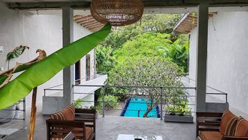 A modern outdoor seating area with a pool, surrounded by lush greenery.
