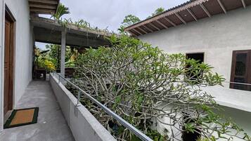 A building with a concrete balcony, a metal railing, and a variety of plants.