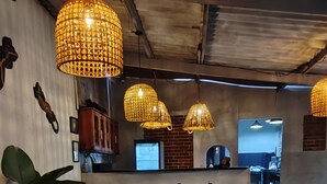 Ein Essbereich mit einem Holztisch und Stühlen, hängenden Korbstühlen und einer Ziegelwand.