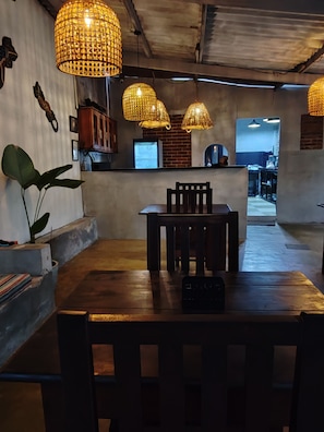 Ein Essbereich mit einem Holztisch und Stühlen, hängenden Korbstühlen und einer Ziegelwand.