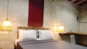 Ein Zimmer mit einem Bett, zwei Pendelleuchten, einem roten Wandbehang mit Muster und einem hölzernen Kopfteil.
