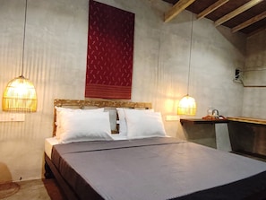 Ein Zimmer mit einem Bett, zwei Pendelleuchten, einem roten Wandbehang mit Muster und einem hölzernen Kopfteil.