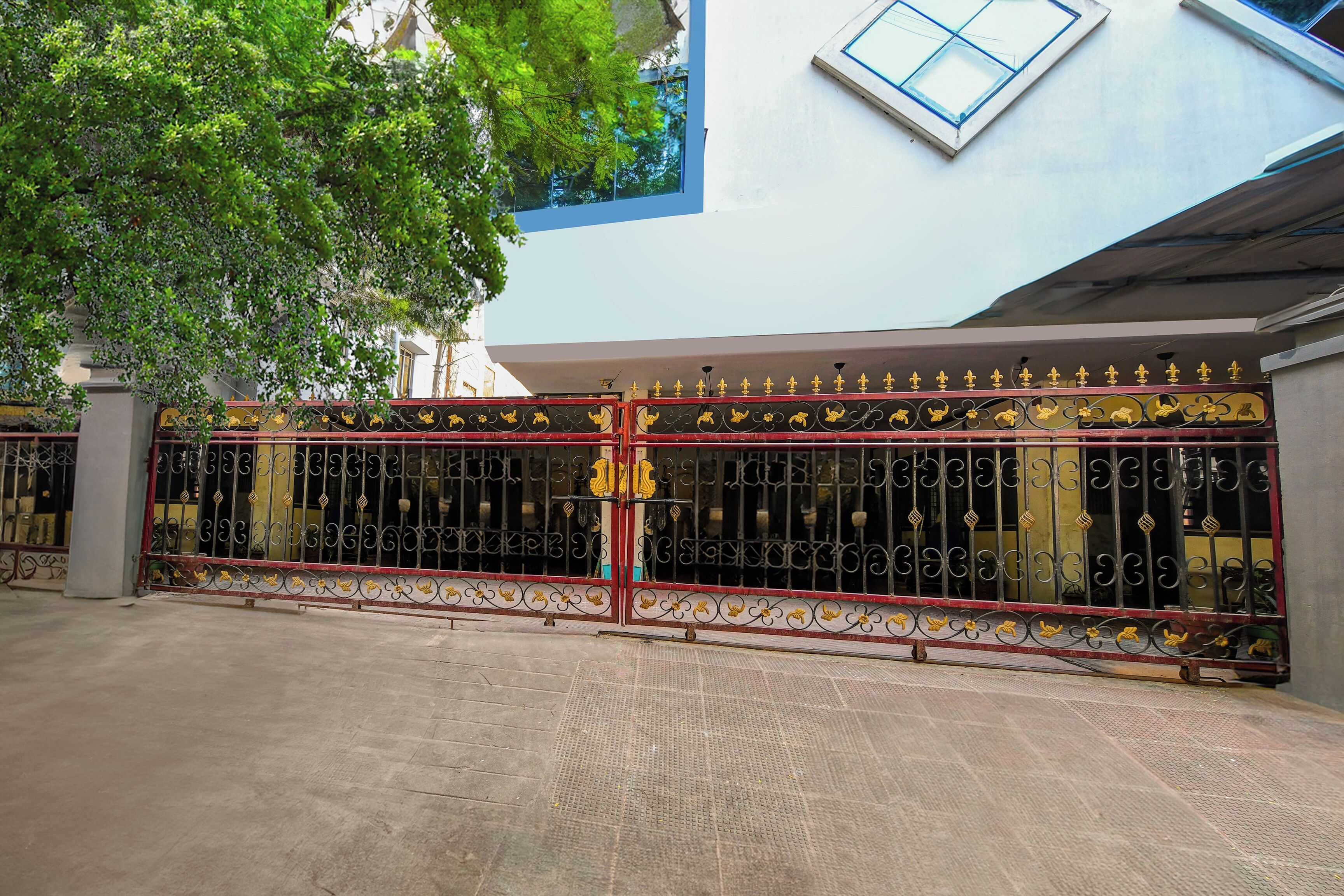A gated entrance with decorative metalwork and a tree in the foreground.