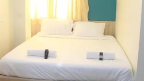 A neatly made bed with white linens and two pillows, an air conditioning unit mounted on the wall, and a window with curtains. - JFIVE RESIDENCY (Chennai)