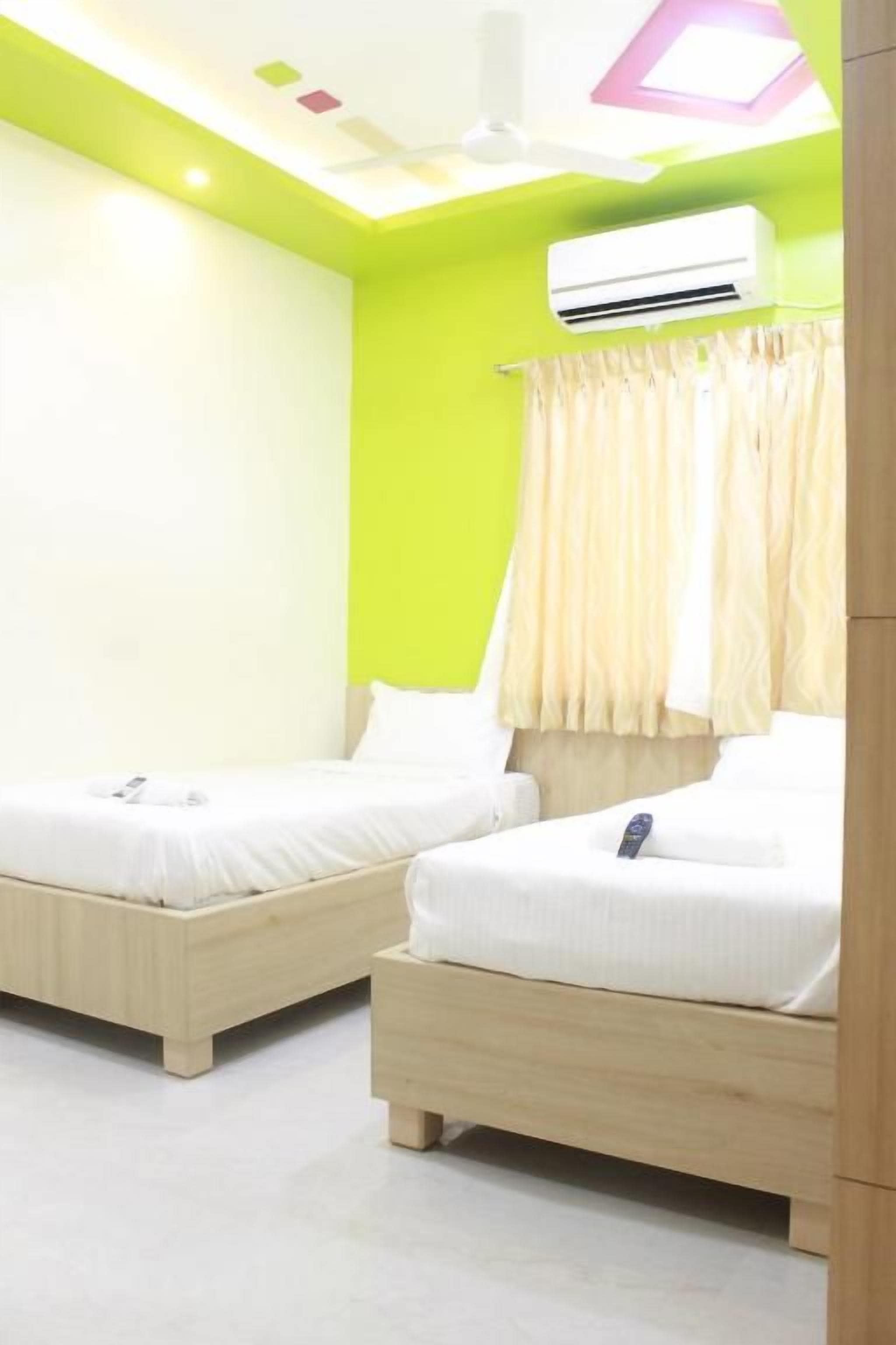 Quarto com duas camas de madeira, ventilador de teto e ar condicionado.