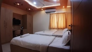 A hotel room with two beds, a television, a desk, and an air conditioning unit. - JFIVE RESIDENCY (Chennai)