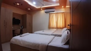 A hotel room with two beds, a television, a desk, and an air conditioning unit. - JFIVE RESIDENCY (Chennai)