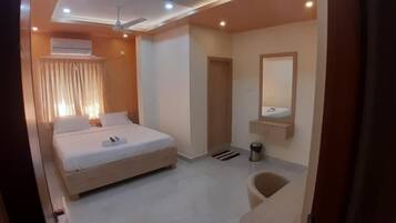 Habitación de hotel con cama, espejo, ventilador de techo y ventana con cortinas.