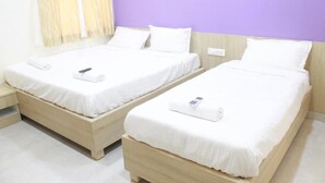 Two single beds with white bedding and a wooden headboard, a bedside table, and a wall with a purple accent. - JFIVE RESIDENCY (Chennai)