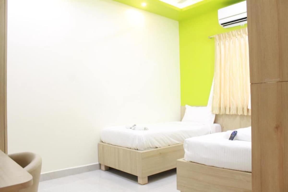 A room with two beds, a wooden desk, and a white chair.