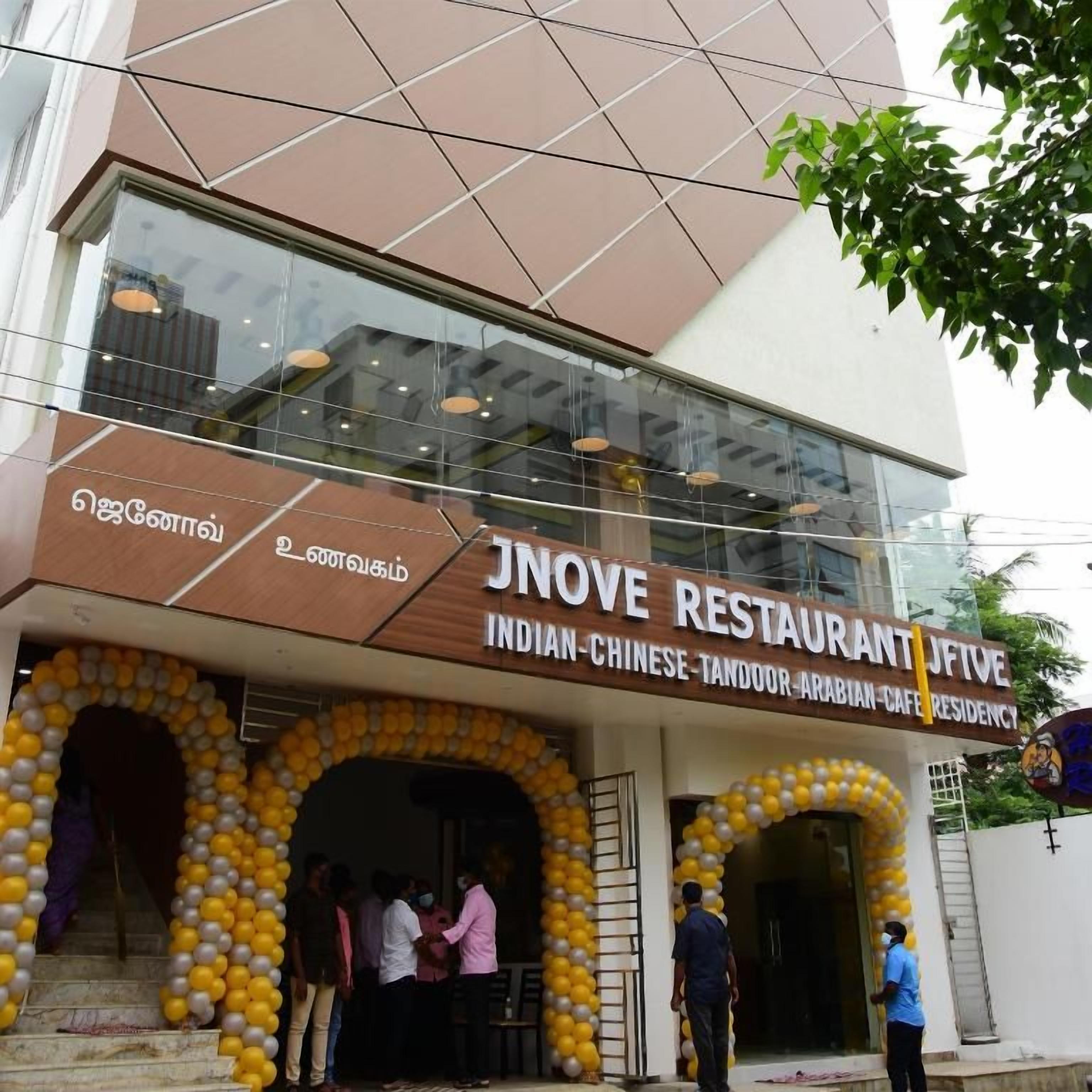 Un restaurant à la façade moderne, une enseigne indiquant qu’il propose une cuisine indo-chinoise, tandoori et arabe, et une entrée en verre.