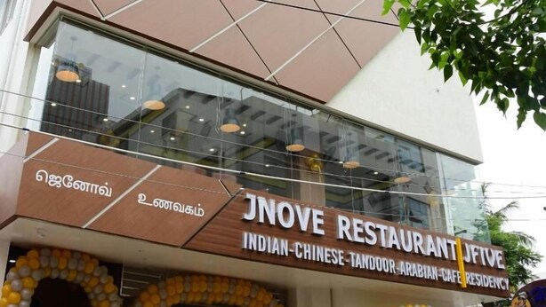 A restaurant with a modern facade, a sign indicating it serves Indian-Chinese-Tandoor-Arabian cuisine, and a glass entrance. - JFIVE RESIDENCY (Chennai)
