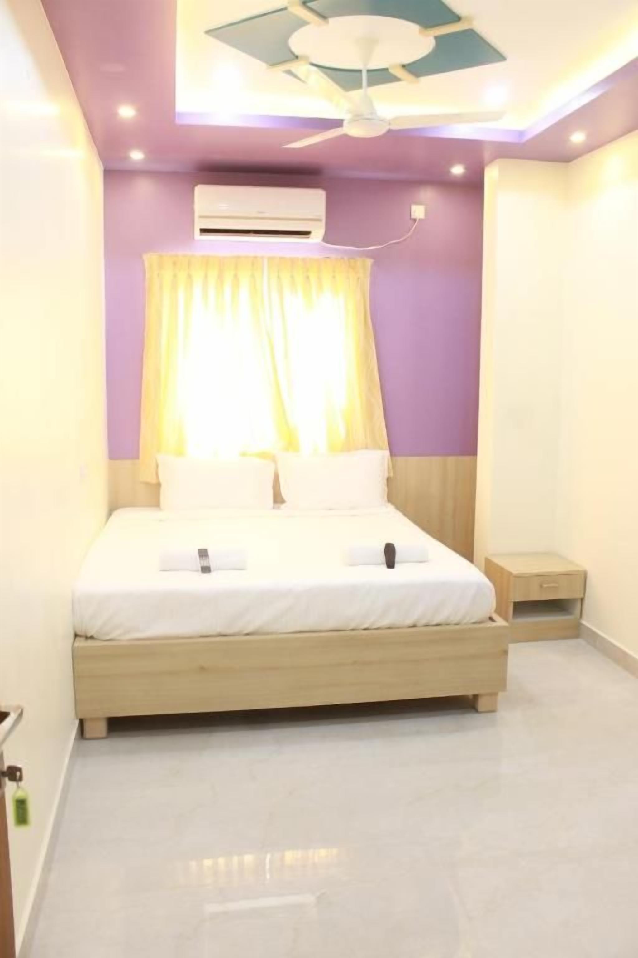Une chambre à coucher comprenant un lit, une table de chevet, un appareil de climatisation et un ventilateur de plafond.