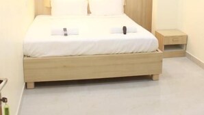 A bedroom with a bed, a nightstand, an air conditioning unit, and a ceiling fan. - JFIVE RESIDENCY (Chennai)