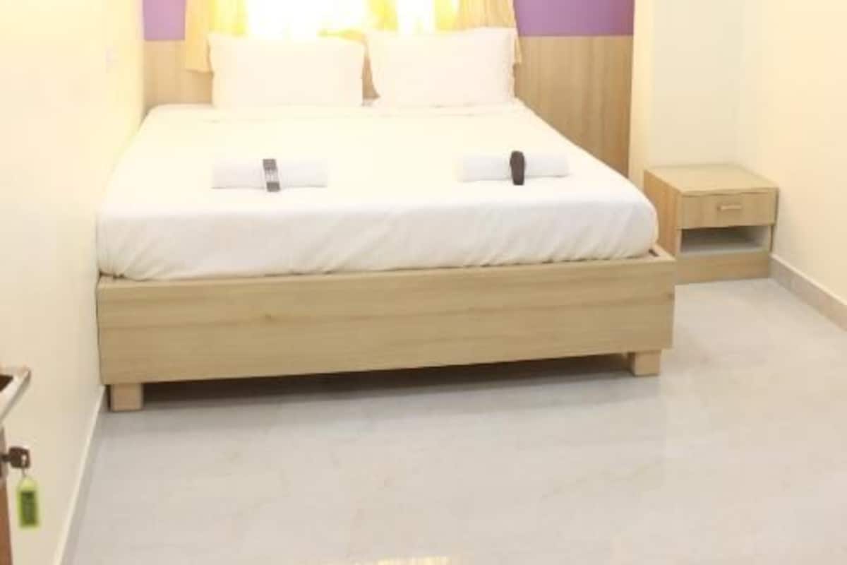 A bedroom with a bed, a nightstand, an air conditioning unit, and a ceiling fan.