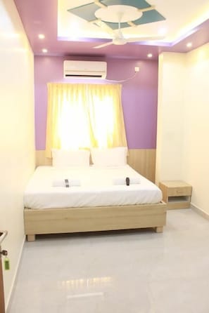 A bedroom with a bed, a nightstand, an air conditioning unit, and a ceiling fan. - JFIVE RESIDENCY (Chennai)
