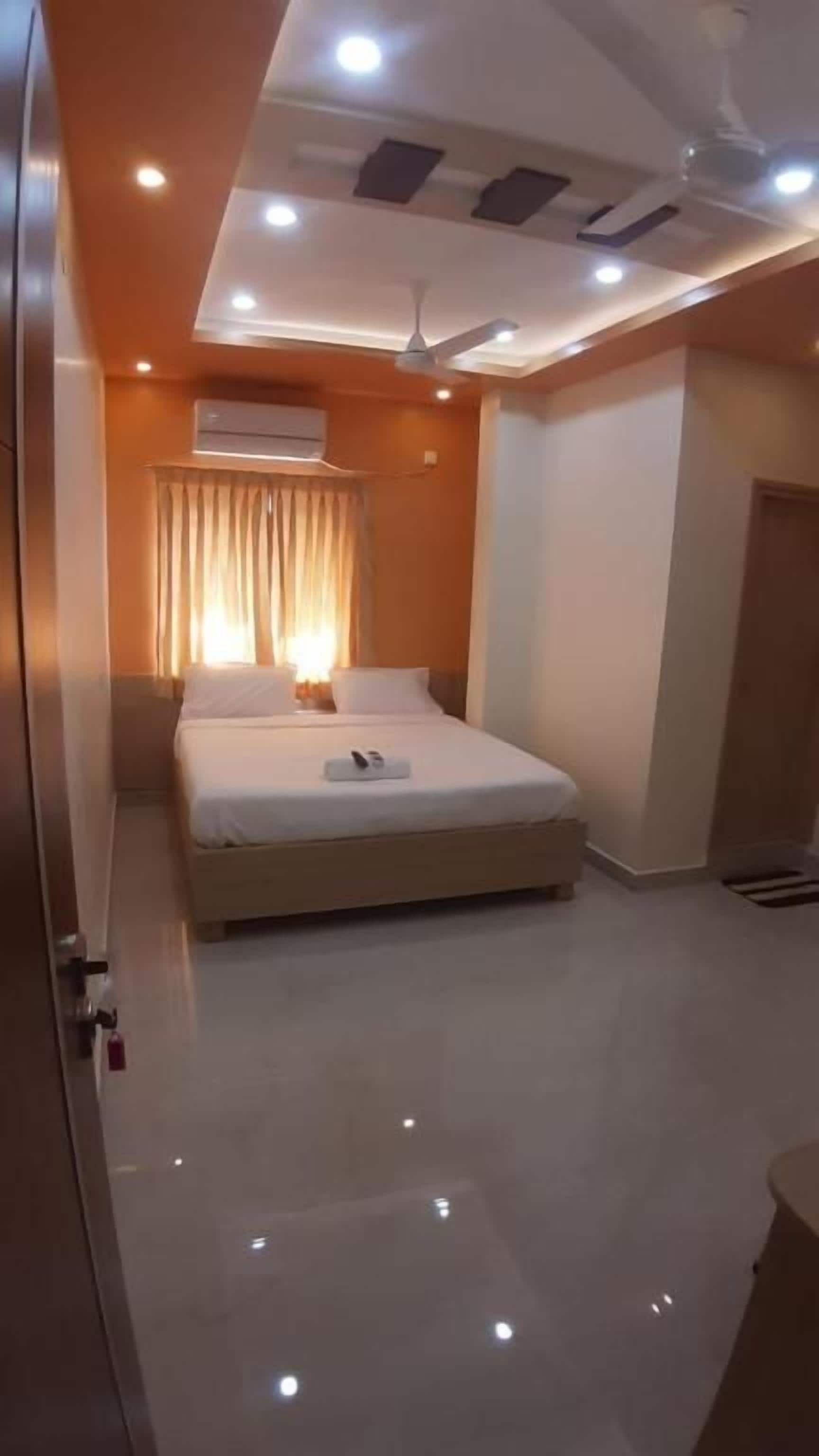 Un dormitorio con cama, ventilador de techo, iluminación empotrada y una ventana con cortinas.