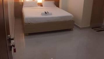 Un dormitorio con cama, ventilador de techo, iluminación empotrada y una ventana con cortinas.